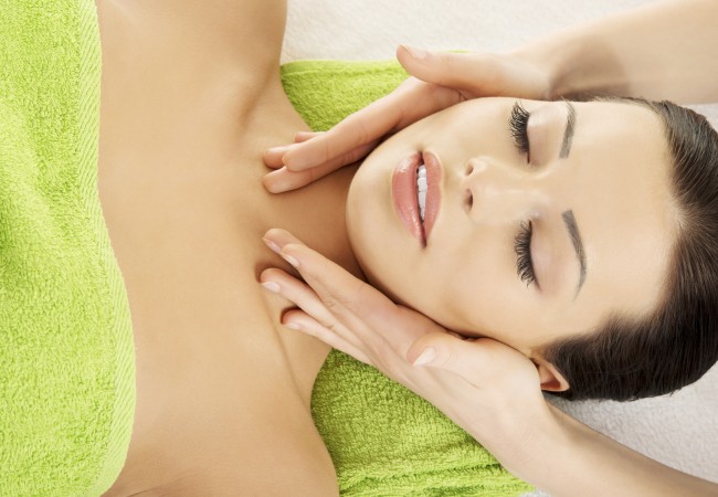 Beautiful young relaxed woman enjoy receiving face massage therapy at spa saloon